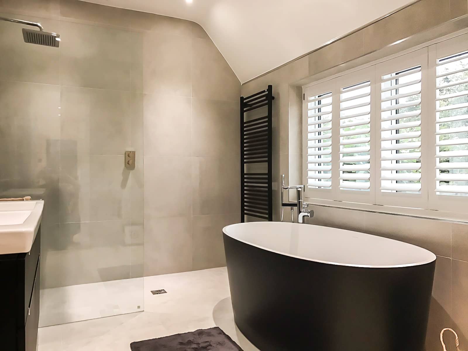 White shutters in a contemporary bathroom with freestanding bath