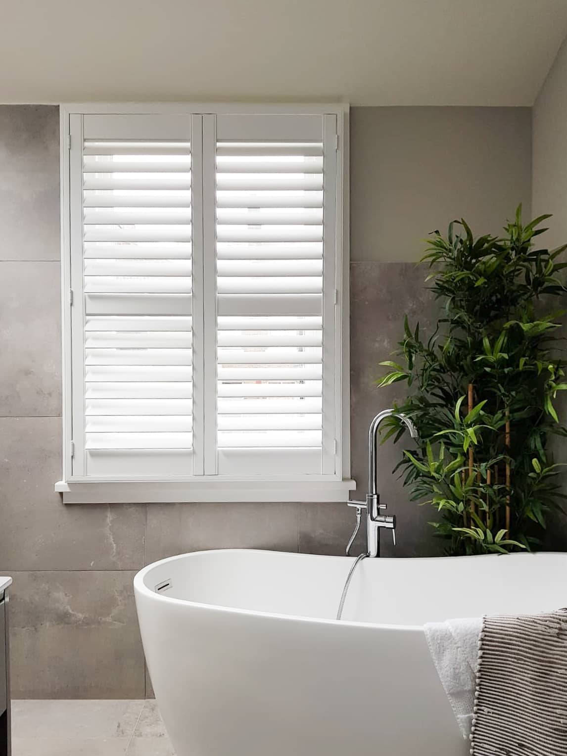 White shutters with mid-rail beside a bathroom bath