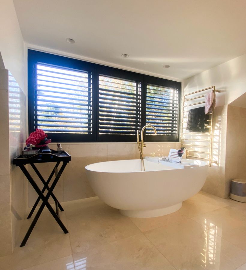 Navy shutters in a modern bathroom with freestanding bath