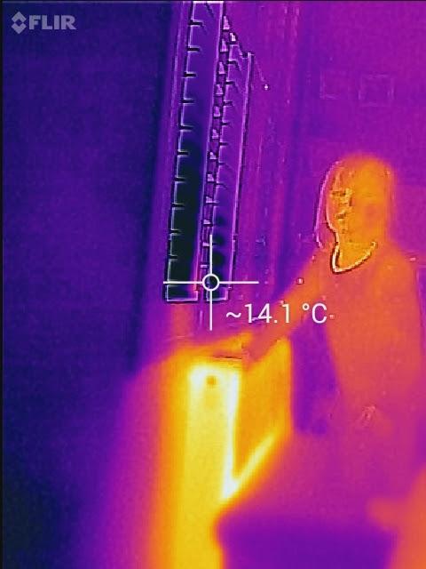 Thermal camera image of a window with shutters and louvres open, showing heat escaping
