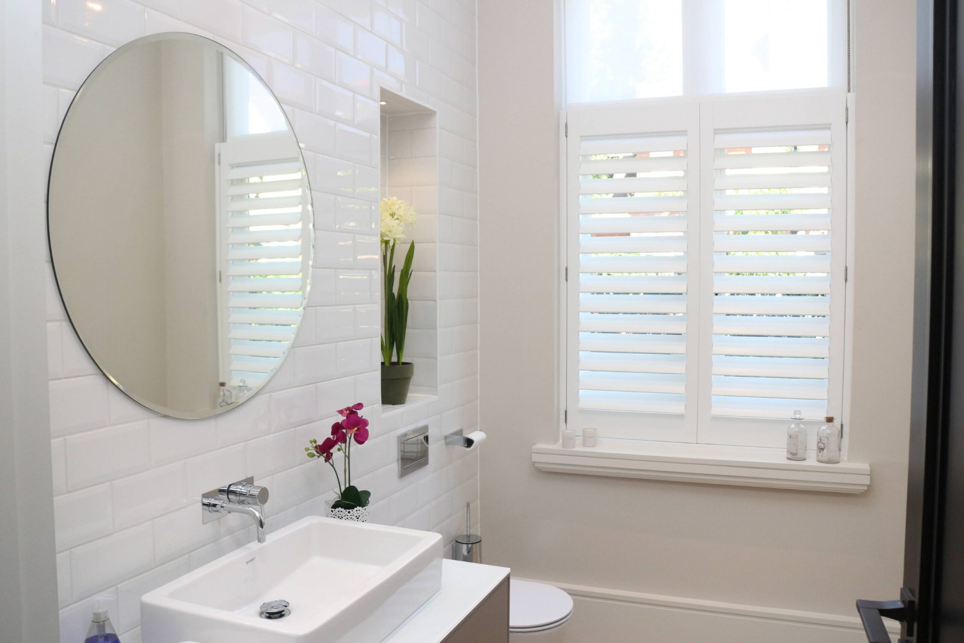 White café-style shutters in a bright bathroom with metro tiles