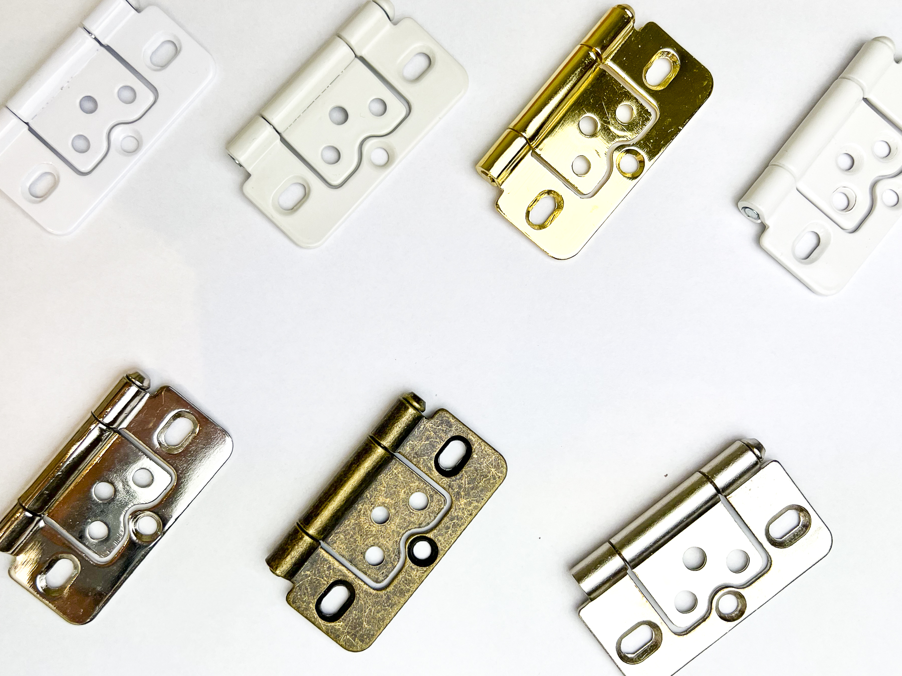 Flat lay of hinge finish options - white, cream, chrome, brass, gold and antique brass